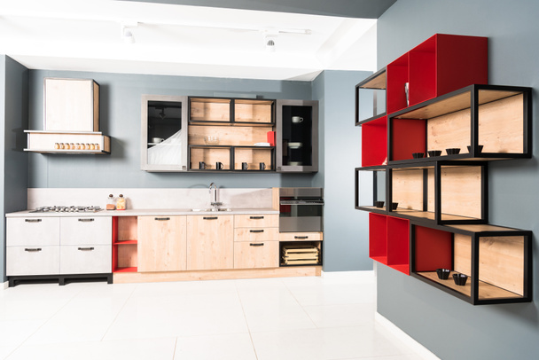Interieur einer modernen sauberen hellen Küche mit Möbeln und roten Holzregalen - Foto, Bild