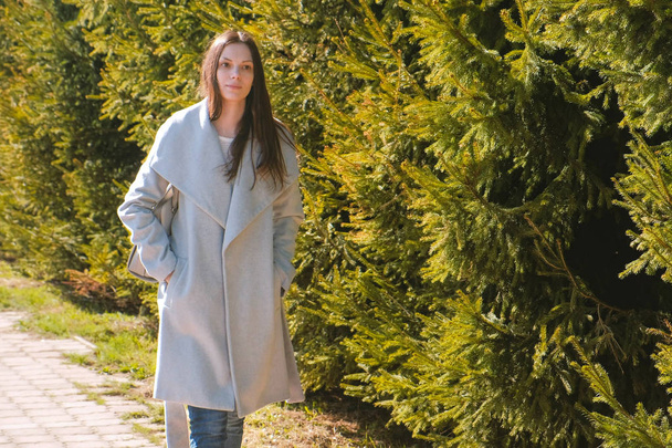 Portrait of tired beautiful brunette woman in coat walking in spring park. - Fotoğraf, Görsel