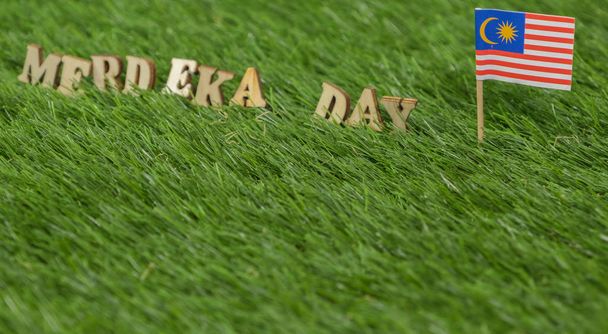 Miniature Malaysian flag with MERDEKA( or Independence) DAY text on green grass,  Conceptual image. - Photo, Image