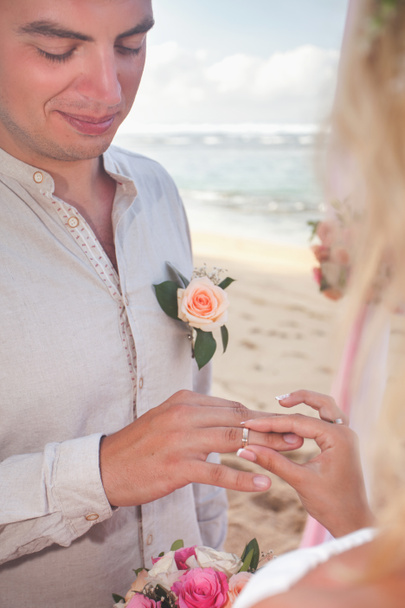 Jonggehuwde paar zetten trouwringen op handen - Foto, afbeelding