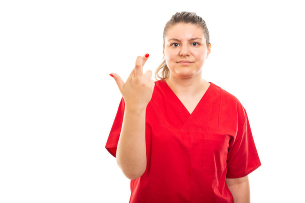 Portré fiatal egészségügyi nővér visel piros bozót kereszt ujjak elszigetelt fehér background copyspace hirdetés terület bemutatás - Fotó, kép