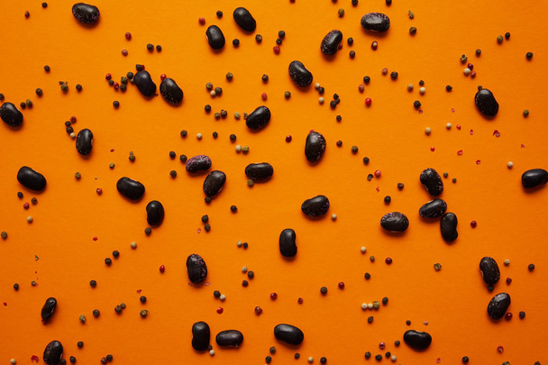 top view of haricot beans and peppercorns on orange background - Φωτογραφία, εικόνα