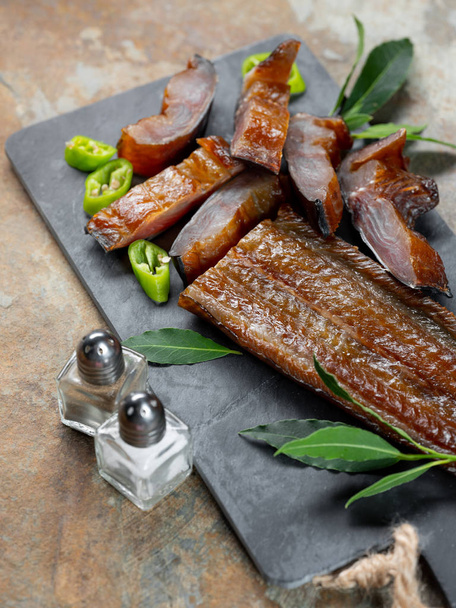 Smoked sea fish with green pepper and laurel on board background - Fotografie, Obrázek