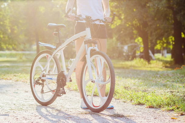 Jovem mulher esportiva com uma bicicleta em um pôr do sol, fundo foco suave
 - Foto, Imagem