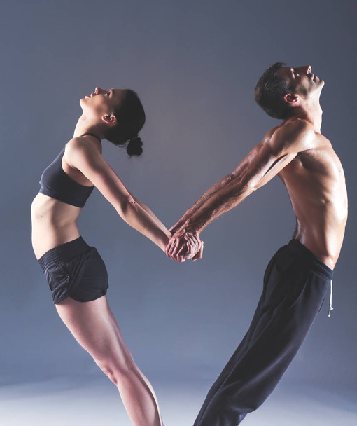 Young couple practicing acro yoga on mat in studio together. Acroyoga. Couple yoga. Partner yoga. - Fotó, kép