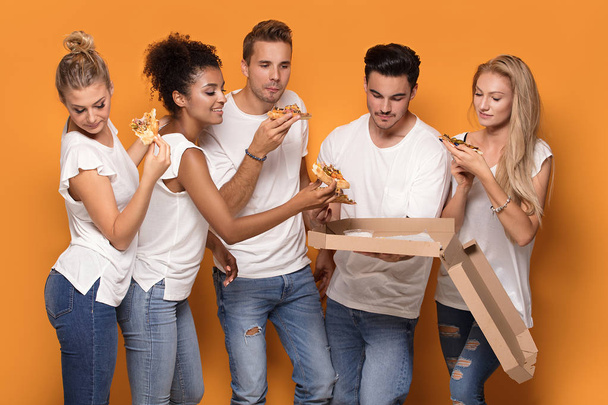 Group of multiracial friends eating pizza and having fun together. - Foto, imagen