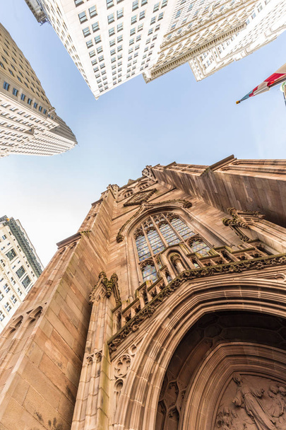 Wide angle upward view of Trinity Church at Broadway and Wall Street with surrounding skyscrapers, Lower Manhattan, New York City, USA - Fotografie, Obrázek