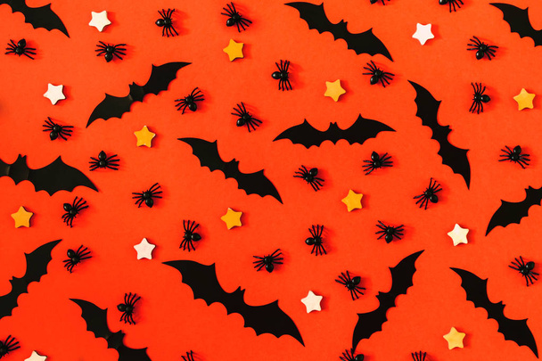 En una superficie de color naranja brillante, muchas arañas negras decorativas, murciélagos y estrellas pequeñas están dispuestas. Fondo hermoso de Halloween
. - Foto, Imagen