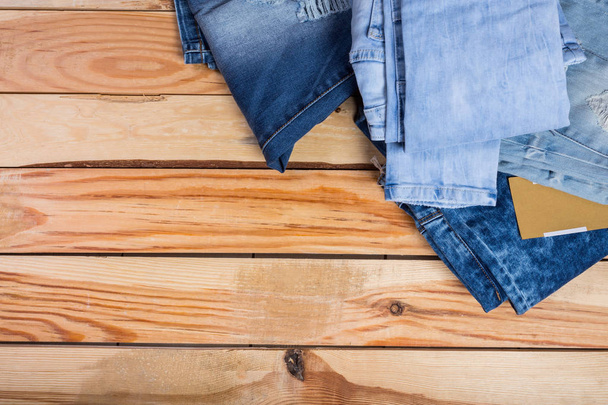 Jeans stacked on wooden background - Zdjęcie, obraz