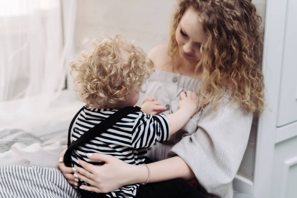 curly, caring young mother playing with her little son, having fun together - Фото, изображение
