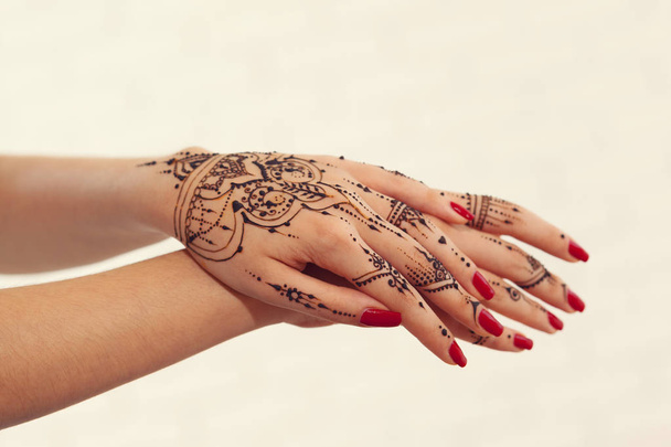 Red manicured hands with Mehndi design, close-up - 写真・画像