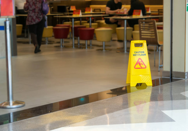 żółty plastikowy stożek z znak ostrzegawczy mokra podłoga w restauracji w sklepie - Zdjęcie, obraz