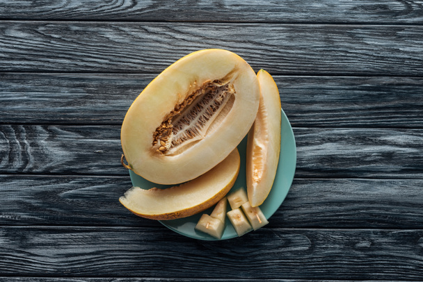 top view of sweet ripe sliced melon on plate on wooden surface  - Foto, immagini
