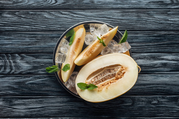 vista superior de melón maduro dulce con menta y cubitos de hielo en la superficie de madera
 - Foto, Imagen