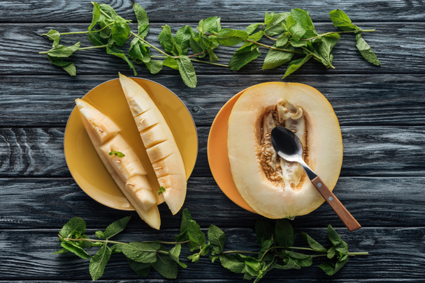 top view of fresh ripe sweet melon with spoon and fresh mint on wooden surface - Photo, Image