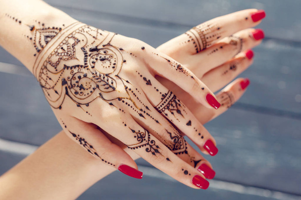 Red manicured hands with Mehndi design, close-up - Valokuva, kuva