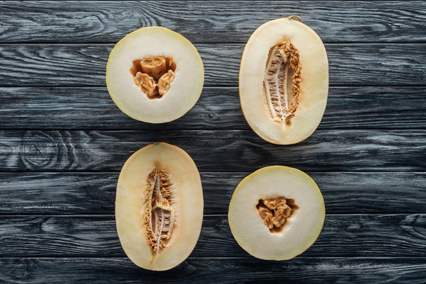 Blick von oben auf halbierte reife süße Honigtau und Cantaloupe-Melonen auf Holzoberfläche  - Foto, Bild