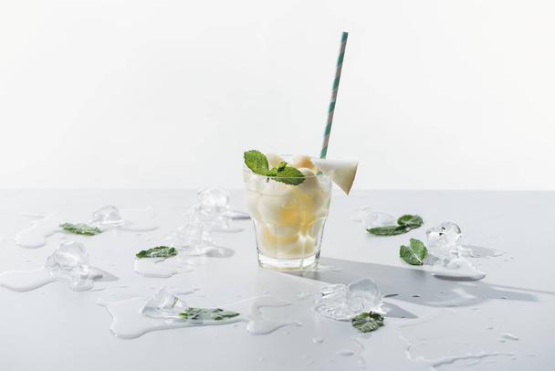 deliciosa bebida de verano con menta y melón en vidrio y cubitos de hielo derretido en blanco
  - Foto, Imagen