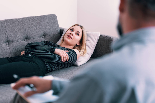 Junge Frau mit Depressionen hört einem Psychotherapeuten während eines Treffens zu - Foto, Bild