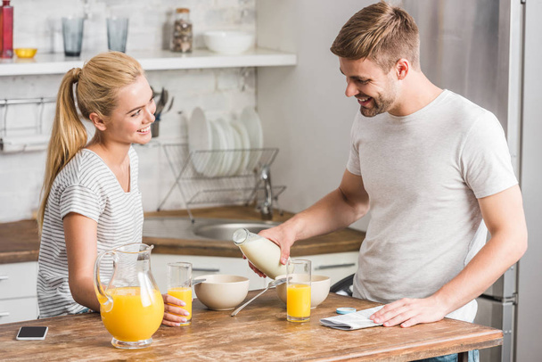 boyfriend pouring milk into plate during breakfast in kitchen - Photo, Image