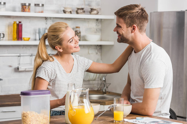 smiling girlfriend touching boyfriend during breakfast in kitchen - Zdjęcie, obraz