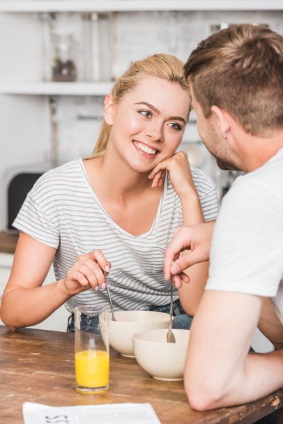 zamyślony uśmiechający się dziewczyna patrząc na chłopaka podczas śniadania w kuchni - Zdjęcie, obraz