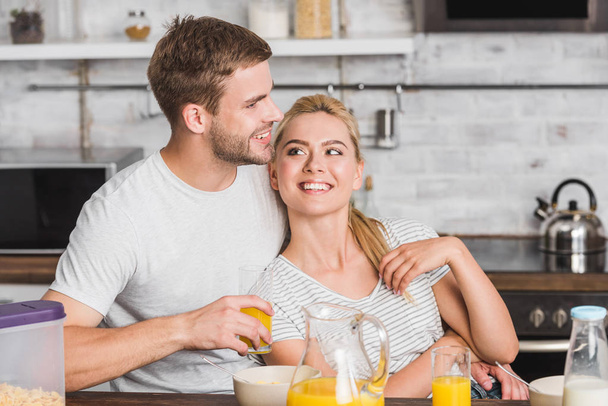 novio feliz abrazo novia atractiva durante el desayuno en la cocina
 - Foto, Imagen