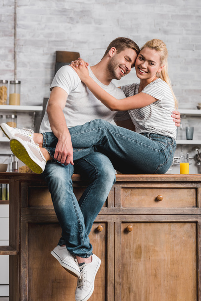 szczęśliwa para przytulanie i siedzi na kuchennym blacie - Zdjęcie, obraz