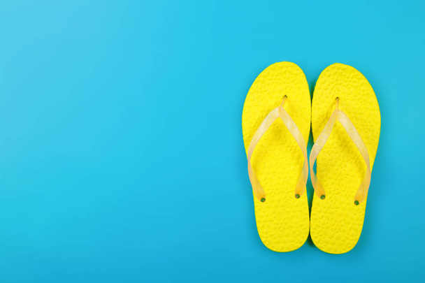 Giysi, Ayakkabı ve aksesuarları - üstten görünüm sarı çift parmak arası terlik sandalet mavi bir arka plan üzerinde - Fotoğraf, Görsel