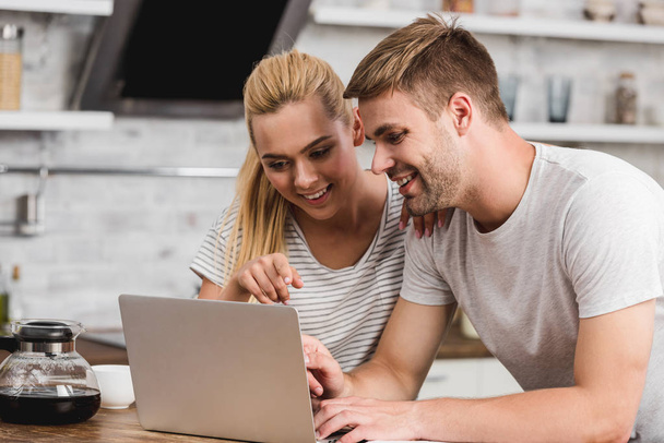 couple looking at laptop together in kitchen - Photo, Image