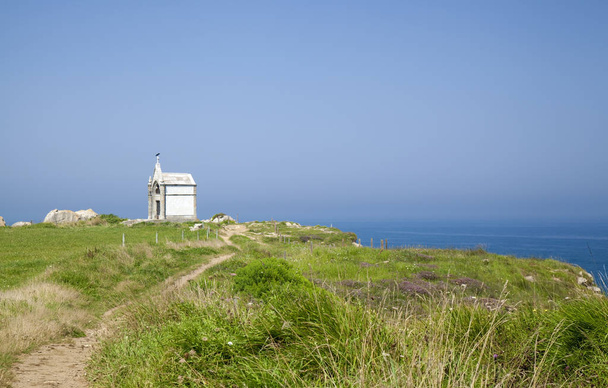 Cantábria, paisagem costeira entre Santander e Maruca, variante de uma parte do Caminho de Santiago, pequeno monumento branco Panteon del Ingles nas falésias
 - Foto, Imagem