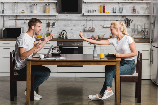 side view of young couple quarreling during breakfast in kitchen  - Fotoğraf, Görsel