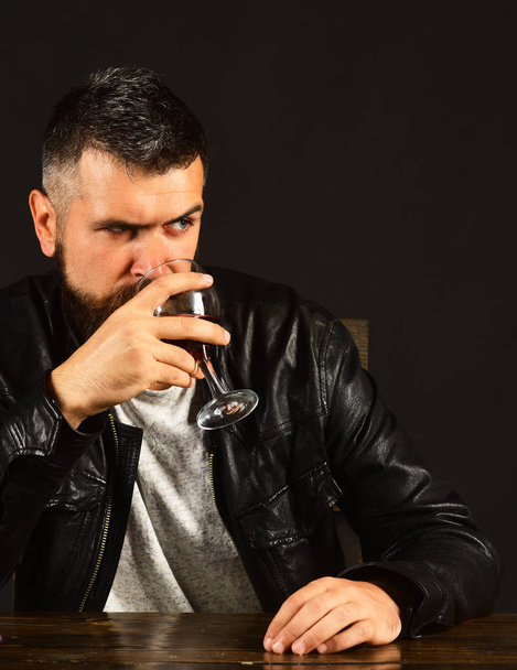 Man with beard holds glass of wine on brown background - Photo, image
