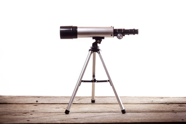 телескоп на білому тлі, покладений на грубу дерев'яну дошку
 - Фото, зображення