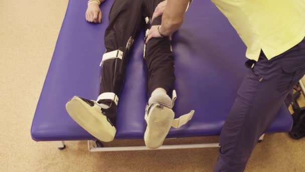 Médico fisioterapeuta poniendo la ortesis para el hombre discapacitado
 - Metraje, vídeo