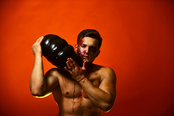 Man with serious face and muscular torso on red background, - 写真・画像