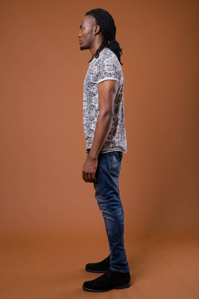 Young handsome African man against brown background - Fotografie, Obrázek