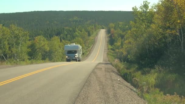 Yakın: yemyeşil yoğun karışık orman hills Kanada vahşi doğada güneşli günde kapsayan boş karayolu boyunca araba beyaz karavan araba. İnsanlar yolculuğa Nova Scotia, Kanada uzak bölgede - Video, Çekim