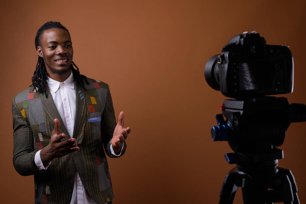 Joven hombre de negocios africano guapo sobre fondo marrón
 - Foto, Imagen