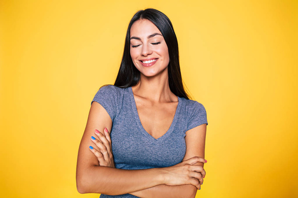 Young woman smiling with closed eyes on yellow background - Fotó, kép