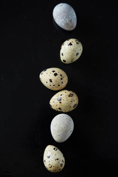 Верхній плаский вигляд ряду перепелиних яєць на чорній смаженій поверхні. Концепція здорового харчування та природної кухні
 - Фото, зображення