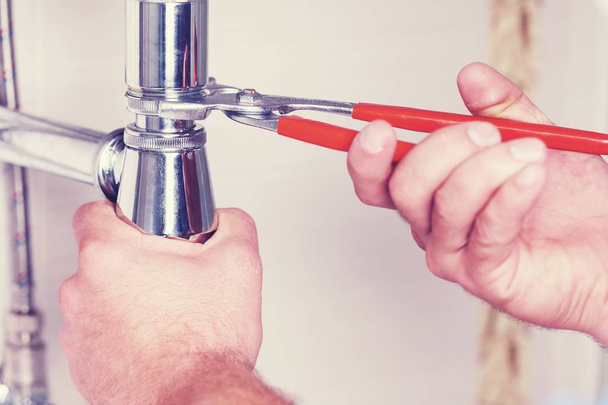Hands of a plumber with sink and wrench. - 写真・画像