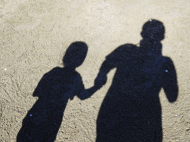 Schaduw van vader en dochter op het strand op het strand, de schaduw van mensen. - Foto, afbeelding