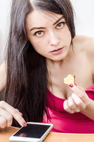Portrait of a beautiful woman looking at the camera eating a cracker - Valokuva, kuva