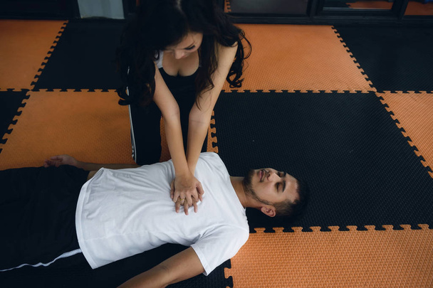 Fitness seksikäs kouluttaja antaa kardiopulmonaalinen elvytys tai CPR (hengenpelastus tekniikoita) sydänkohtaus hukkuminen shokki mies urheiluseurassa. Terveydenhuollon hätäonnettomuuksien käsite
. - Valokuva, kuva