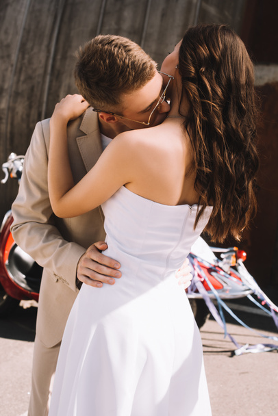 elegant wedding couple kissing and hugging, with scooter on background - Photo, Image