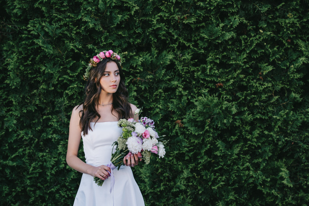 bella sposa in posa in abito bianco tradizionale con corona e bouquet da sposa
 - Foto, immagini