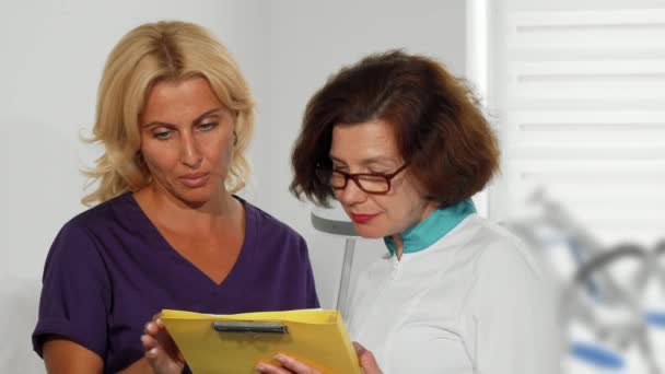 女性医師の診療所で医療調査書類を調べる - 映像、動画