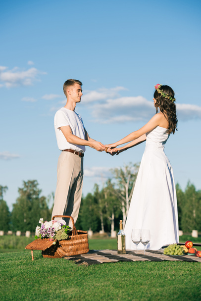 beautiful wedding couple holding hands on picnic - 写真・画像