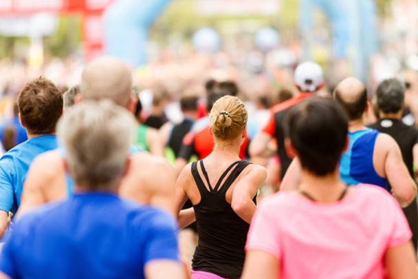 Laufkundschaft beim Marathon. Viele Läufer passieren die Start- oder Ziellinie. Frau im Fokus. - Foto, Bild